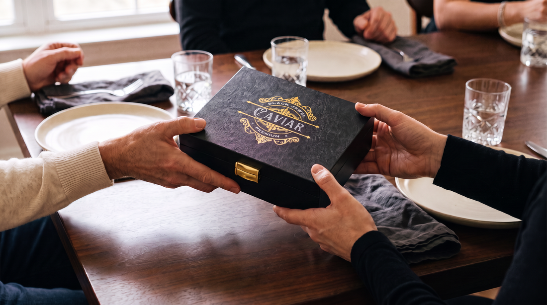 Guests exchanging a Black Jewel Caviar gift box at a warmly lit dinner table