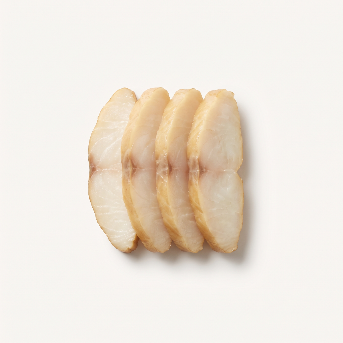four slices of cold-smoked Chilean sea bass, buttery ivory flesh, slightly translucent, delicate beige-golden outer edge