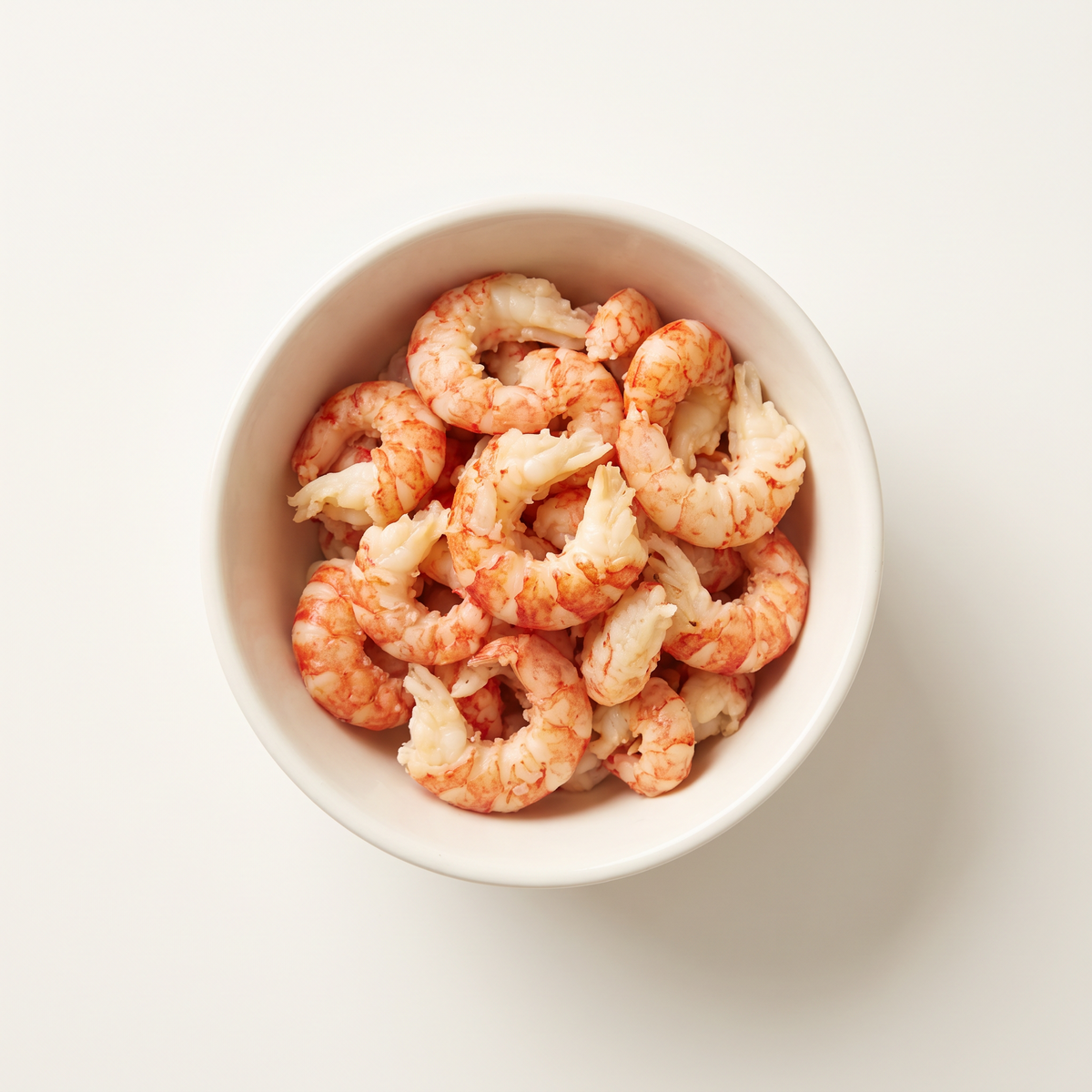 small bowl of peeled cooked crawfish tail meat, curled compact ivory and coral-red tails, no shells, authentic irregular natural sizes