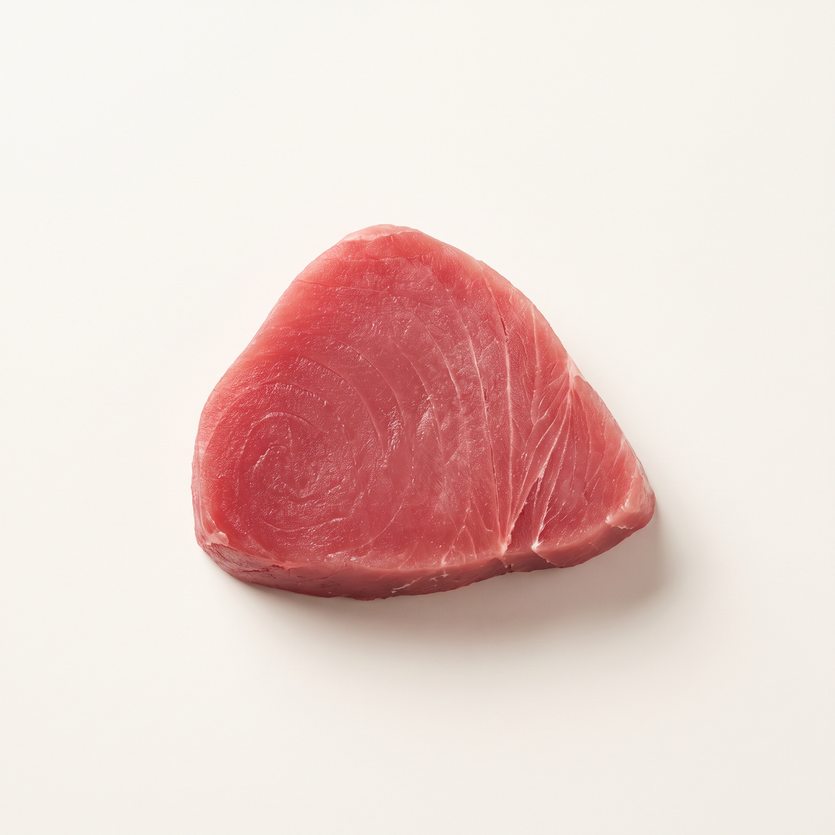 one thick raw eight-ounce tuna steak, deep ruby-pink flesh, clean cut edges and fine muscle grain, uncooked